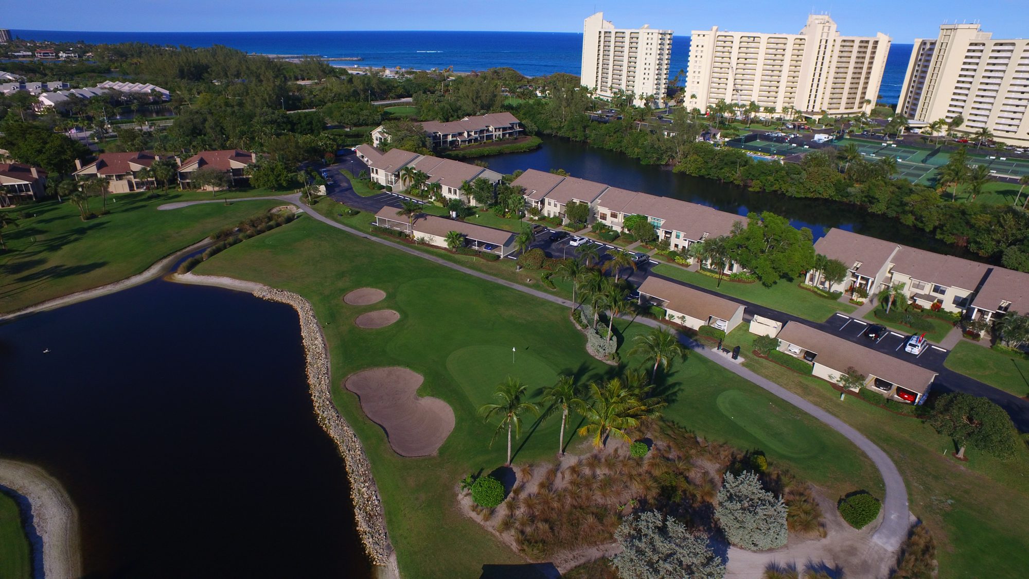 A Jupiter Dunes green beside a lake and condominiums