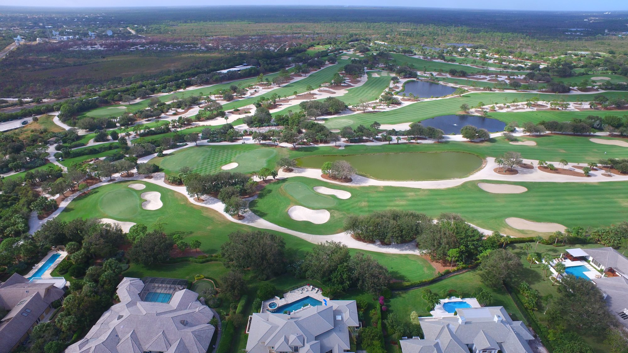 Jupiter Hills fairways and homes leading toward the clubhouse and the water