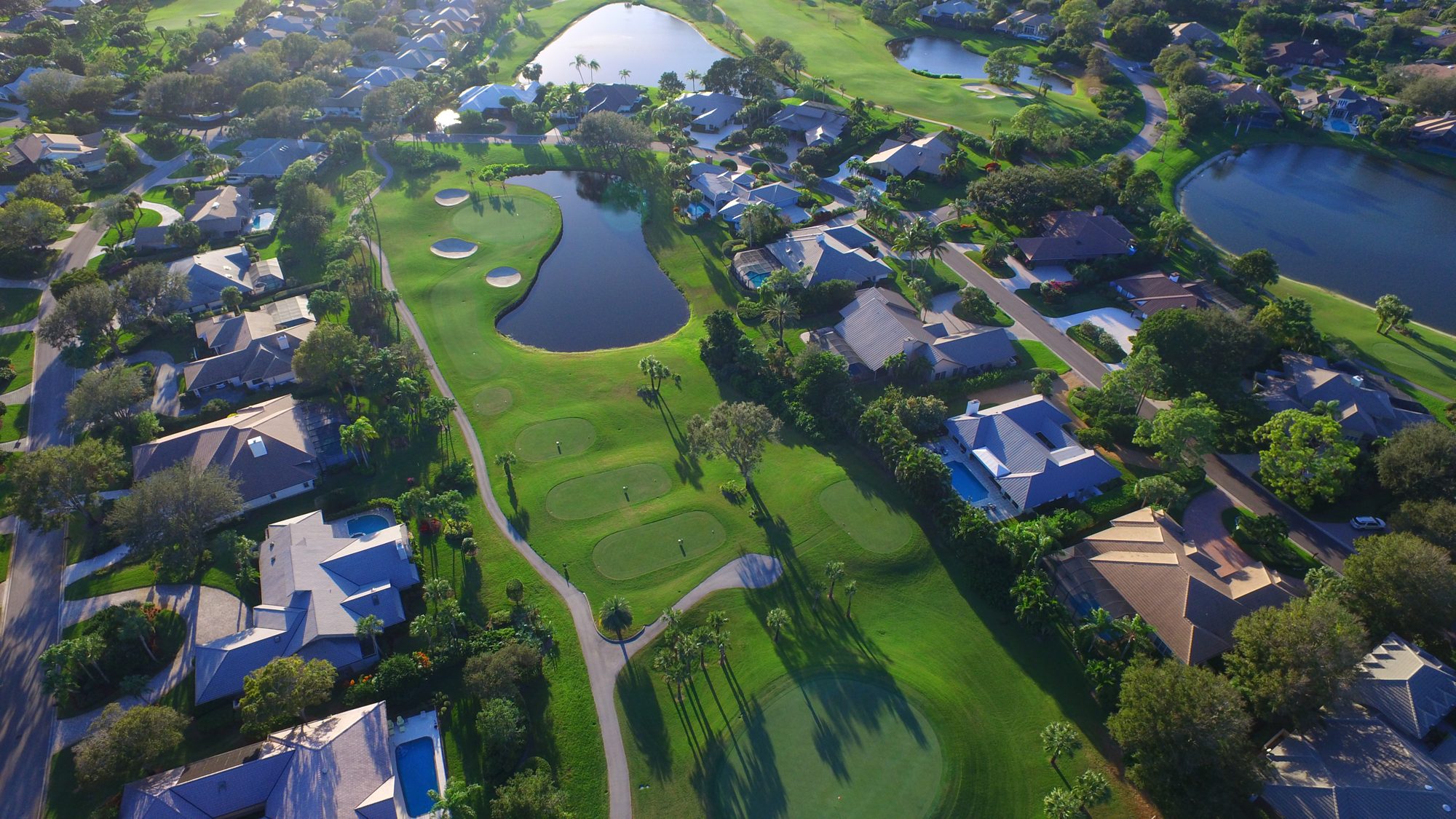 A Mariner Sands green between lakes with the clubhouse and fountain beyond
