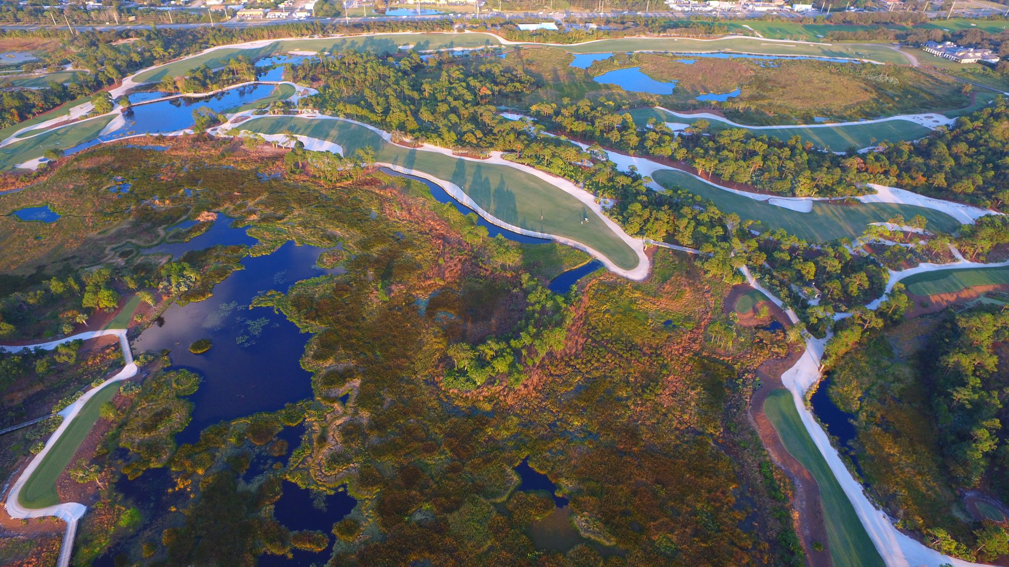 Medalist fairways winding beside a wide marsh at sunrise