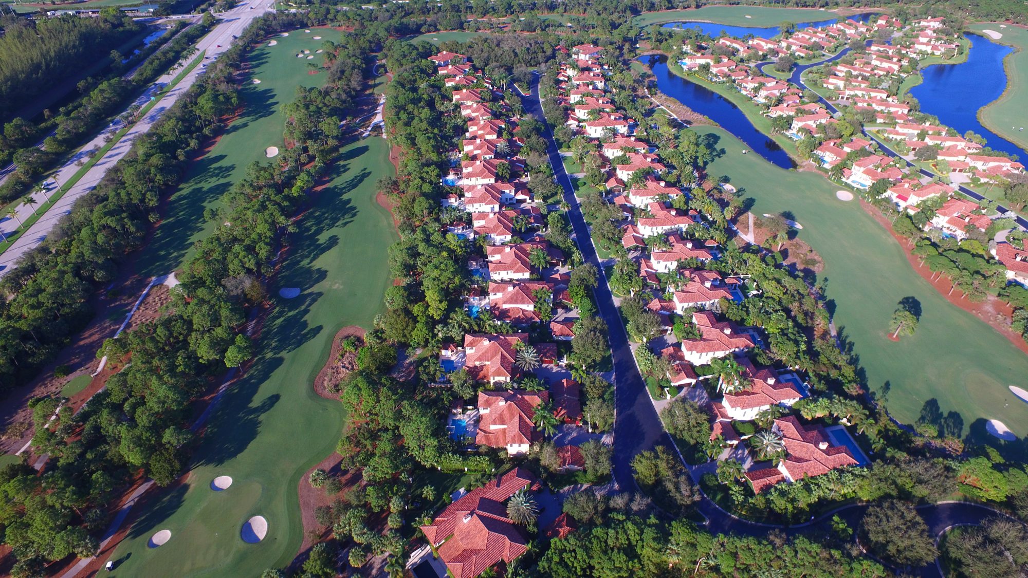 Rows of tile-roofed homes between two fairways