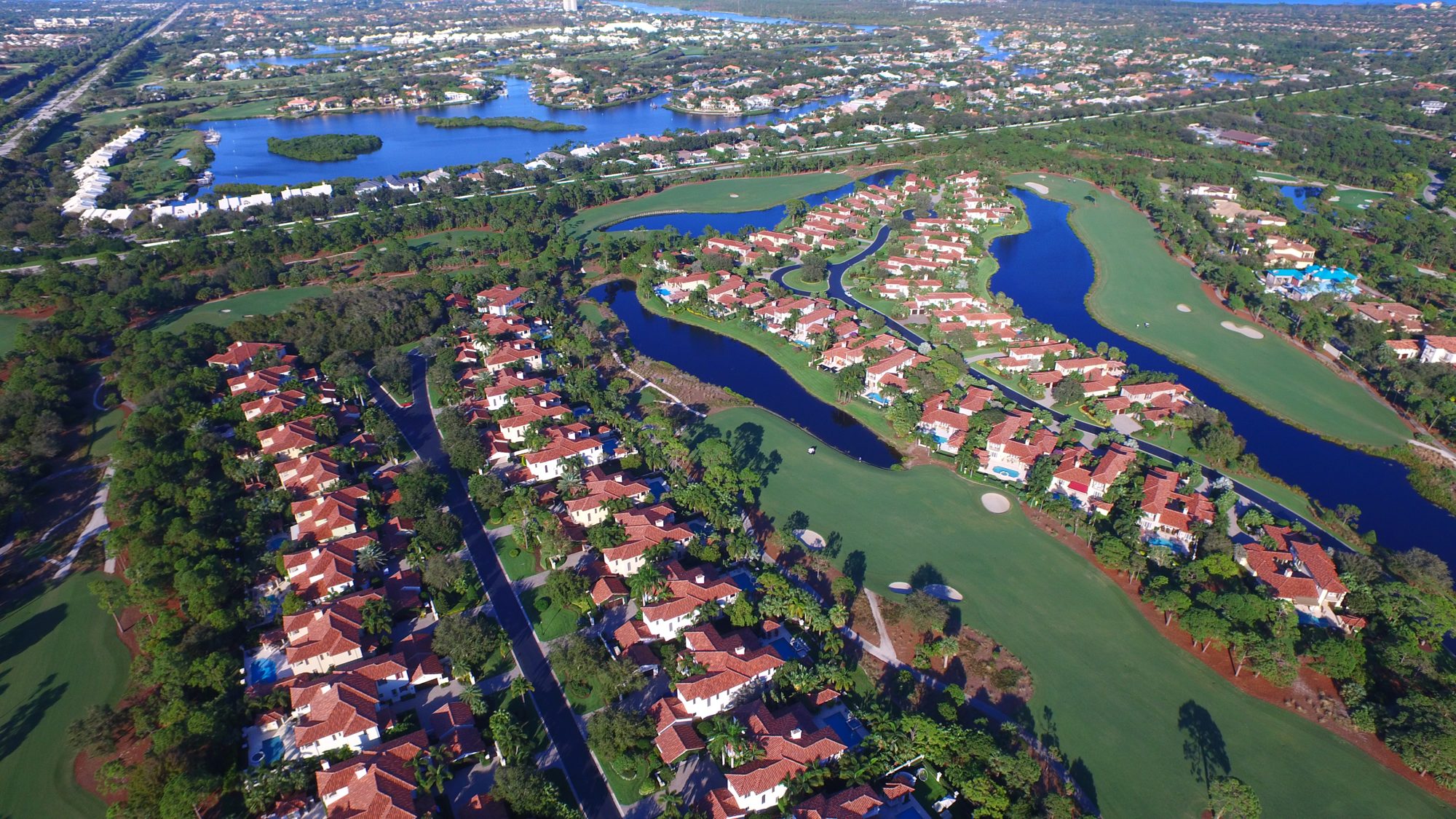 A Trump National Jupiter fairway with white bunkers beside a lake and homes